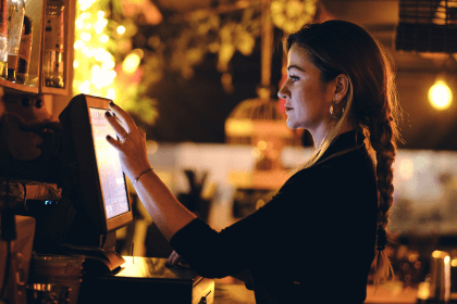 restaurant worker standing at a POS screen entering information